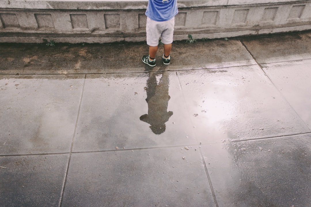 child in blue shirt and white shorts standing on gray concrete floor