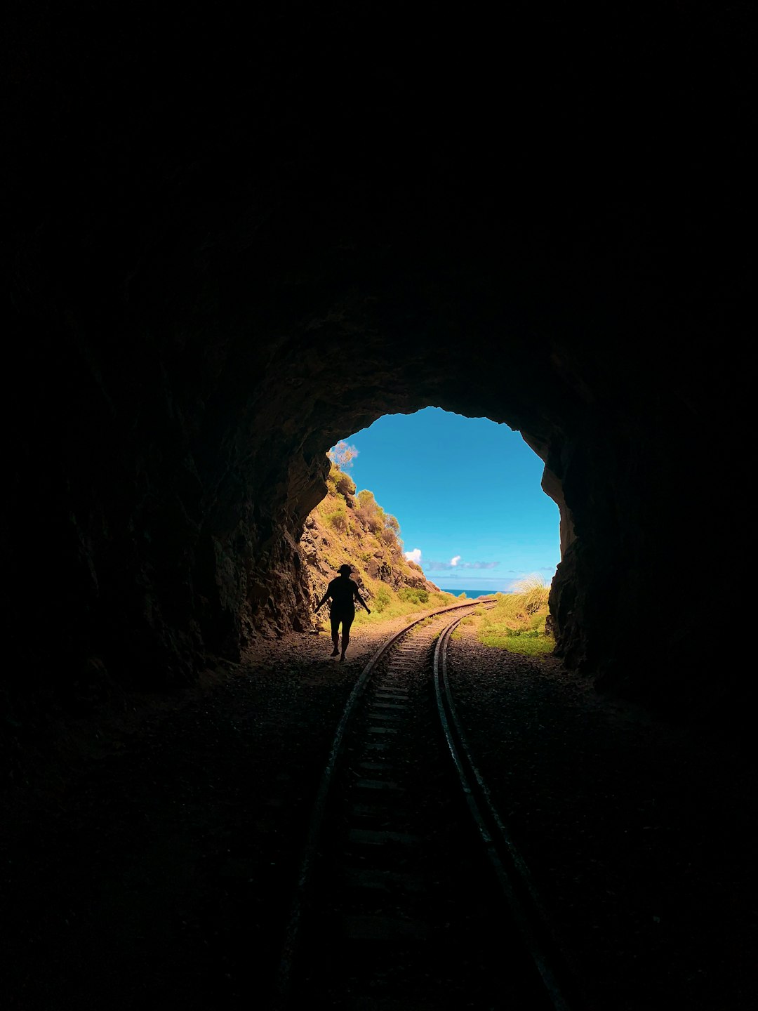silhouette of man walking on tunnel during daytime
