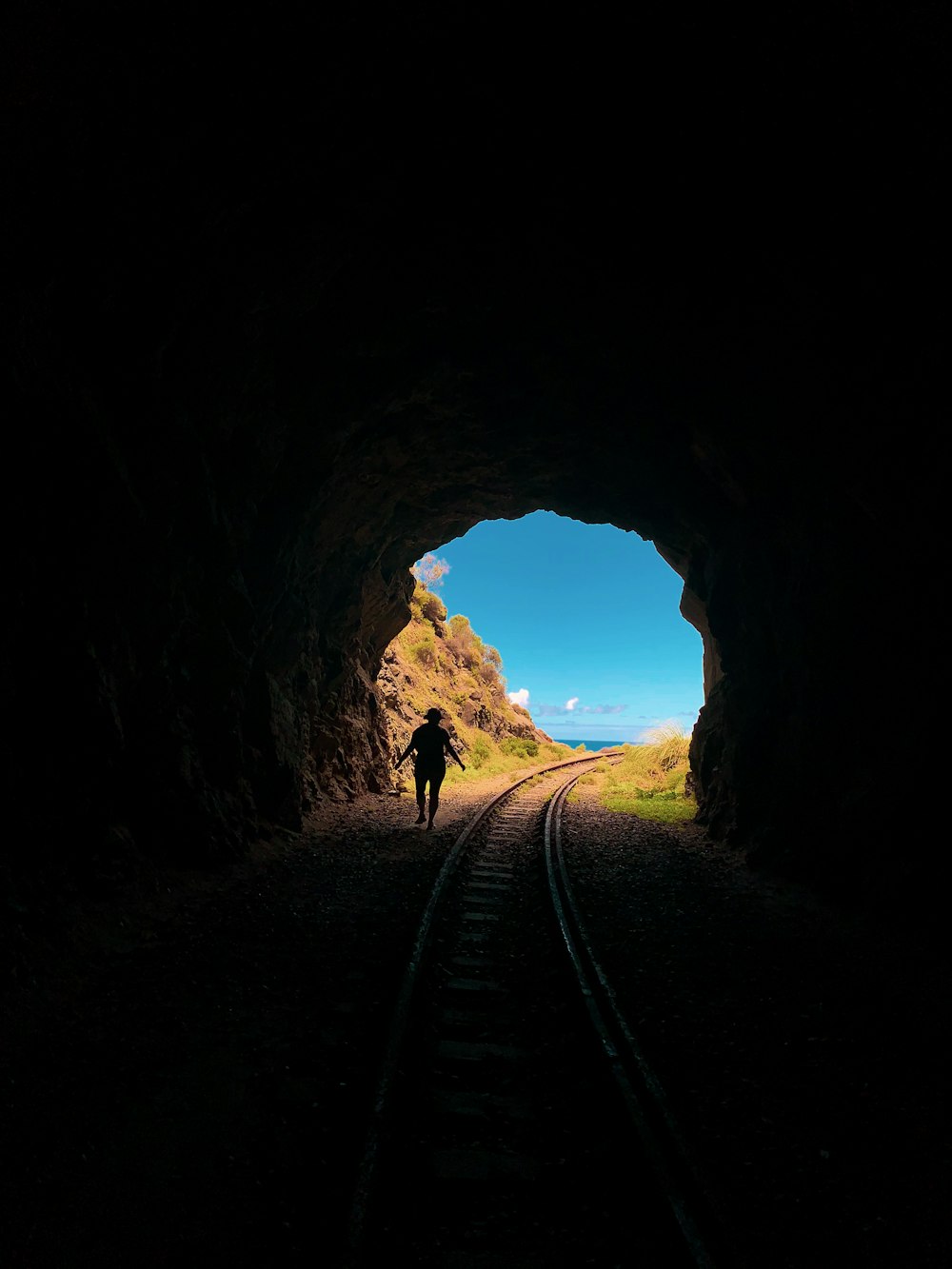 silhouette of man walking on tunnel during daytime