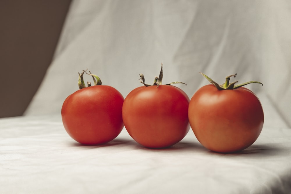 3 red tomato on white textile