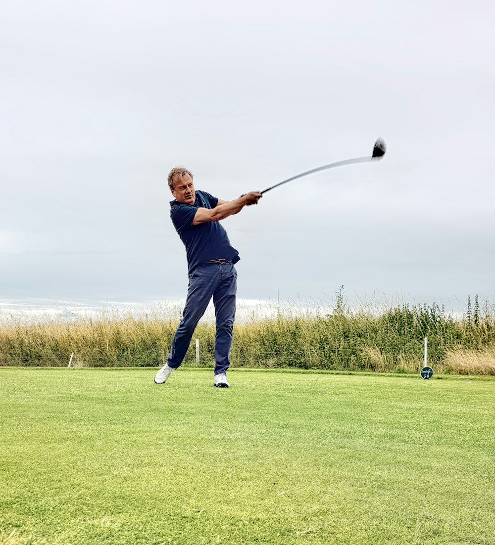 Man in black jacket and blue denim jeans holding golf club on green grass  field during photo – Free Golf Image on Unsplash
