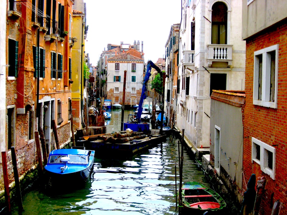 blue and white boat on river between concrete buildings during daytime