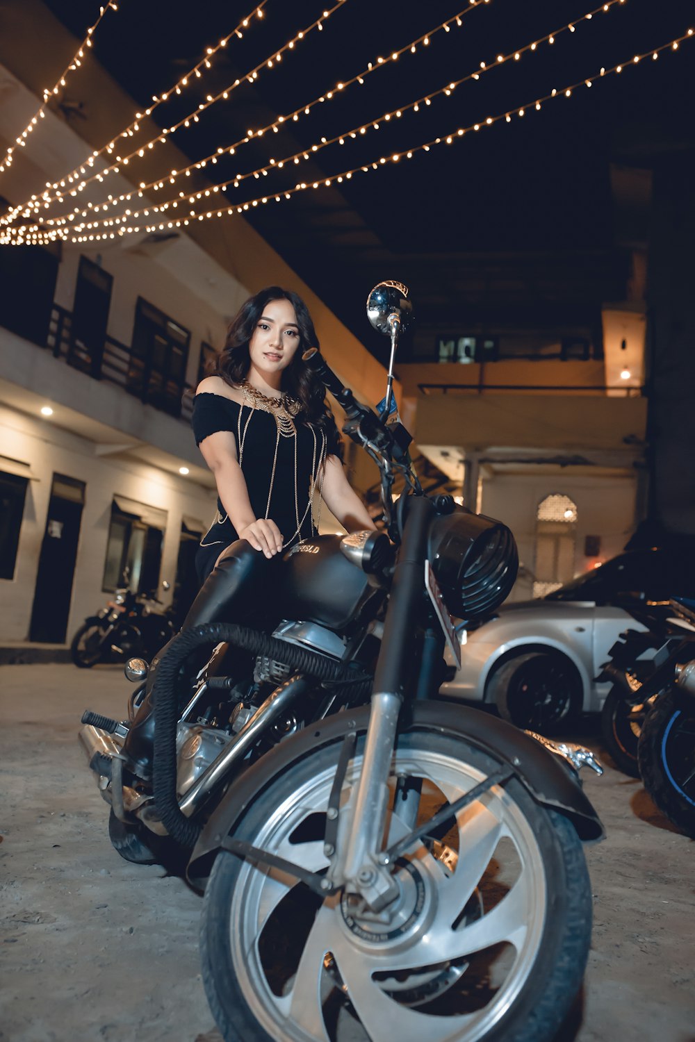 Frau in schwarzem Kleid fährt nachts auf einem schwarzen Motorrad