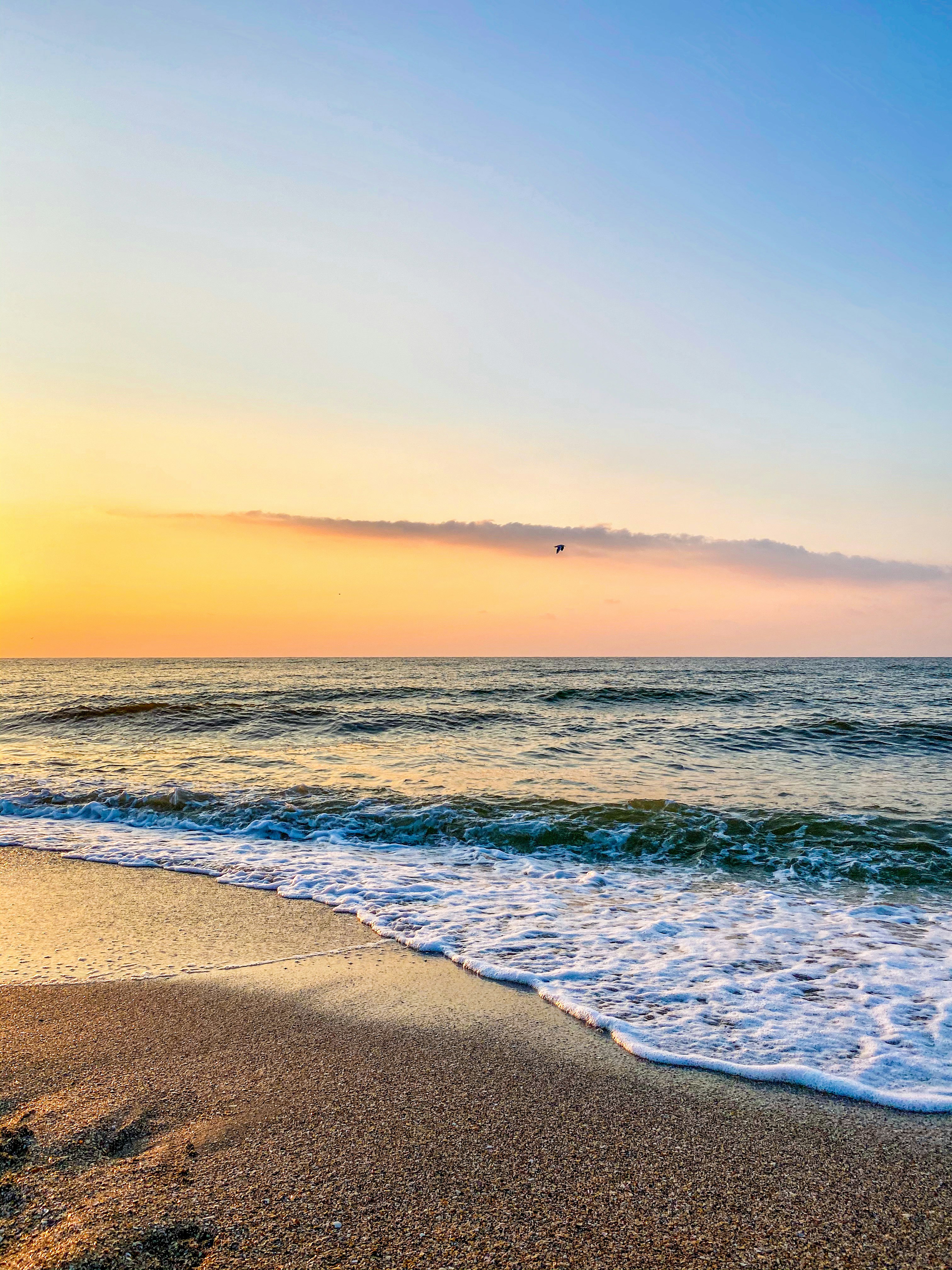 ocean waves crashing on shore during sunset