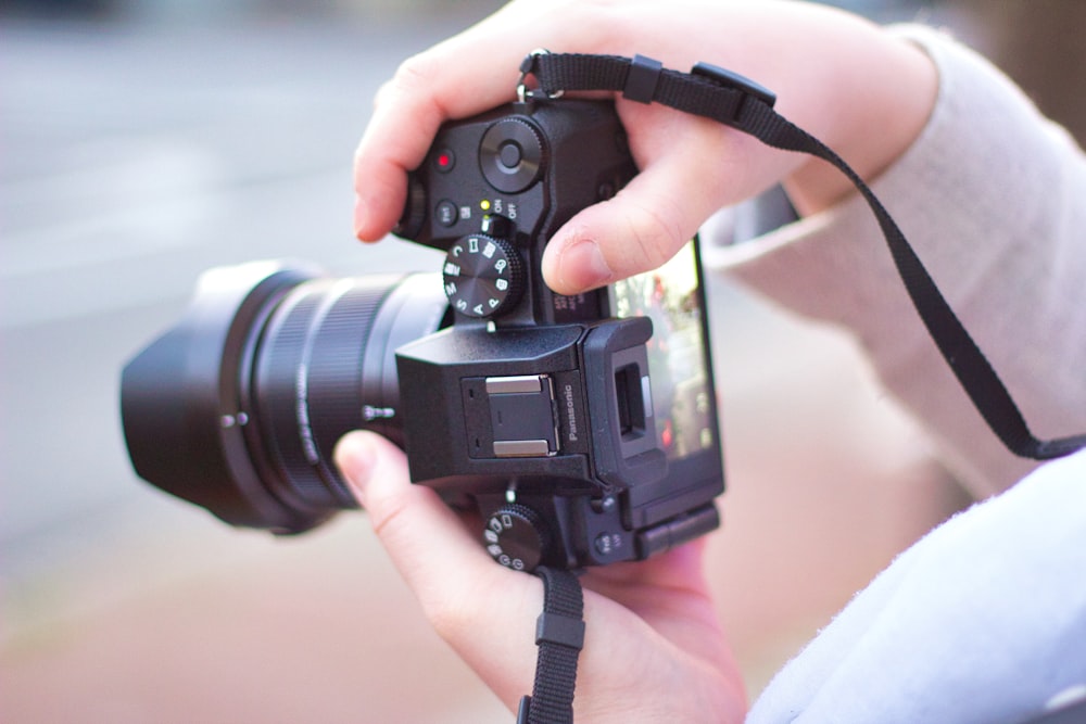 person holding black dslr camera