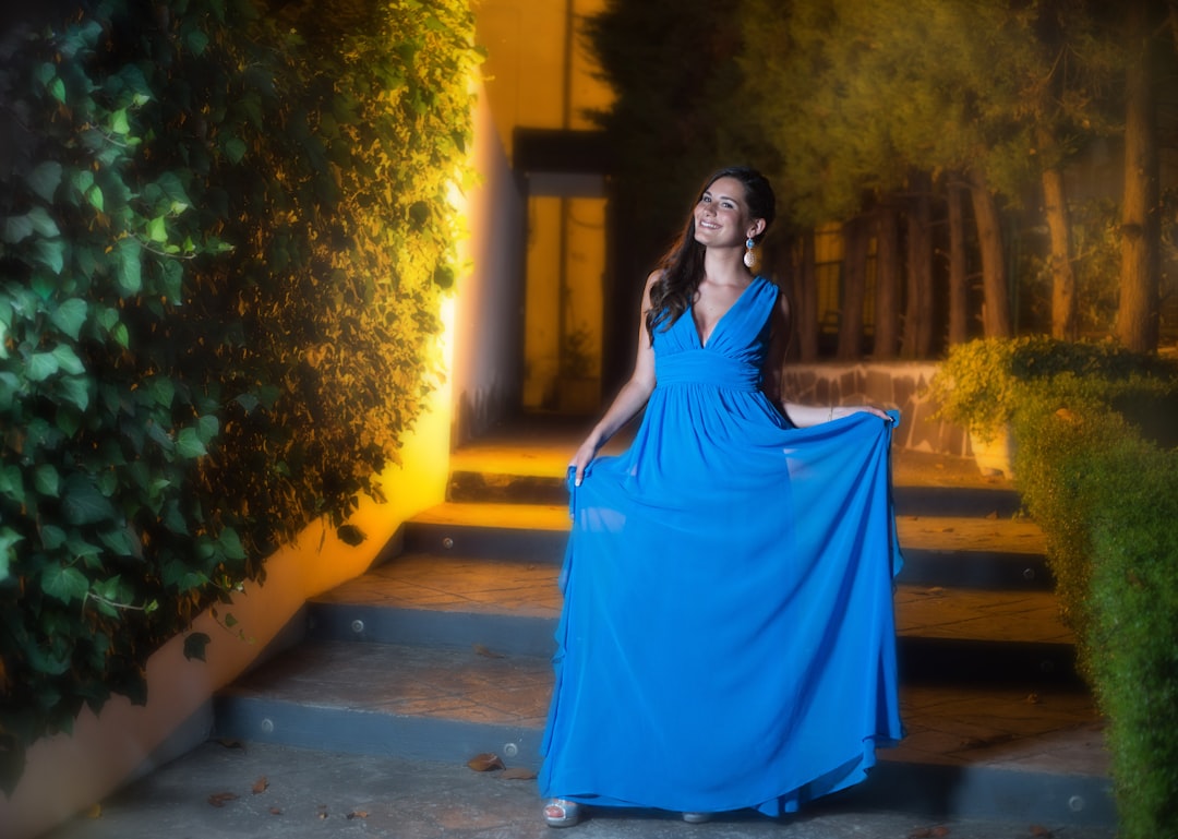 woman in blue sleeveless dress standing on pathway during daytime