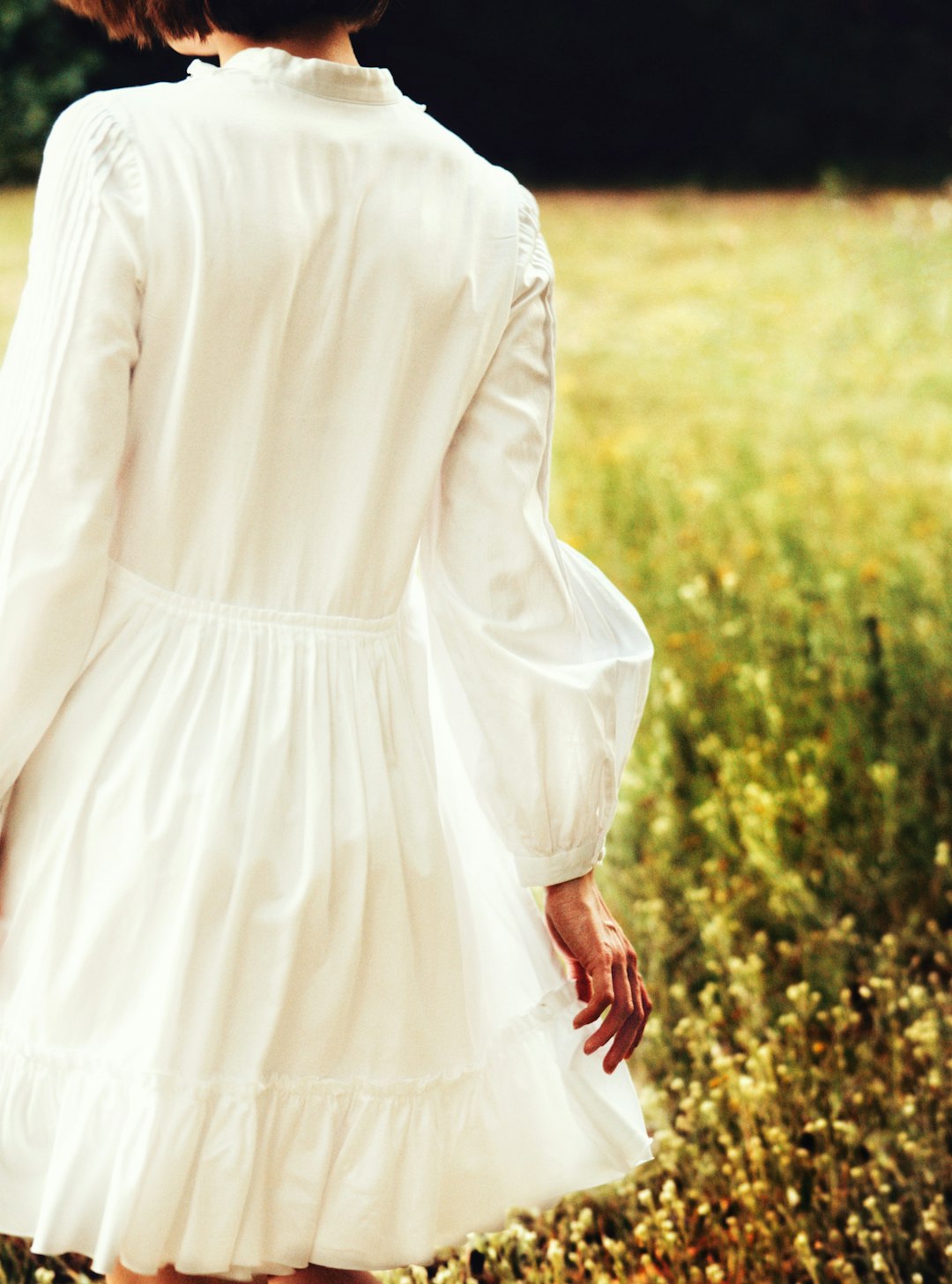 woman in white long sleeve dress standing on green grass field during daytime