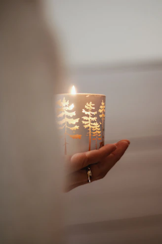 Close-up of a handcrafted candle glowing softly on a wooden table, surrounded by delicate decorations.