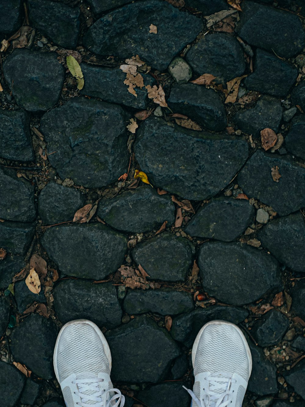 person wearing white and gray sneakers standing on gray concrete floor