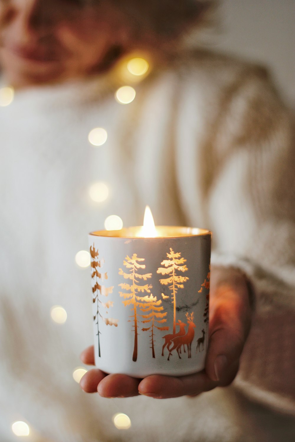 person holding white and red floral ceramic mug