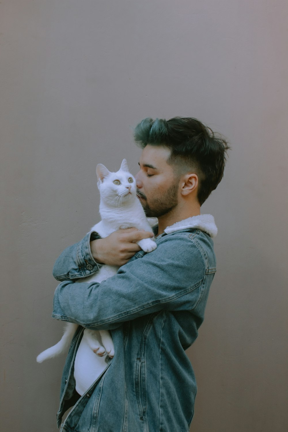 woman in gray jacket carrying white cat