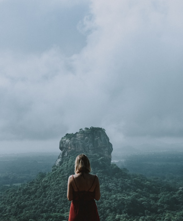 woman in red shirt standing on mountain top