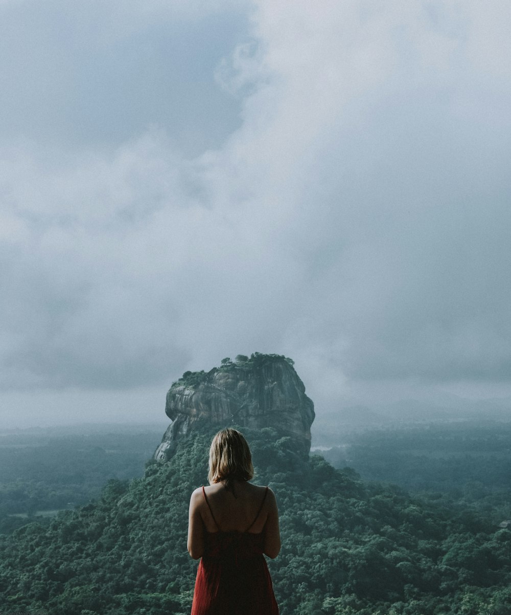 woman in red shirt standing on mountain top