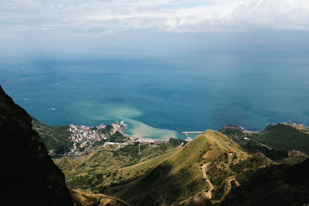 green and brown mountain beside blue sea under blue sky during daytime