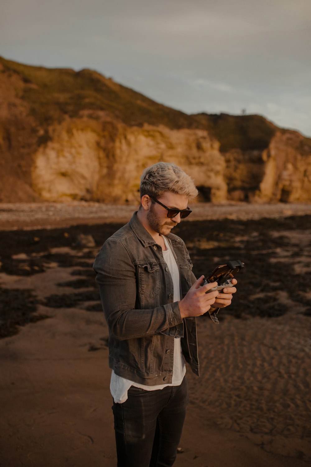 man in gray jacket holding black dslr camera