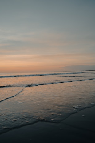 ocean waves crashing on shore during sunset