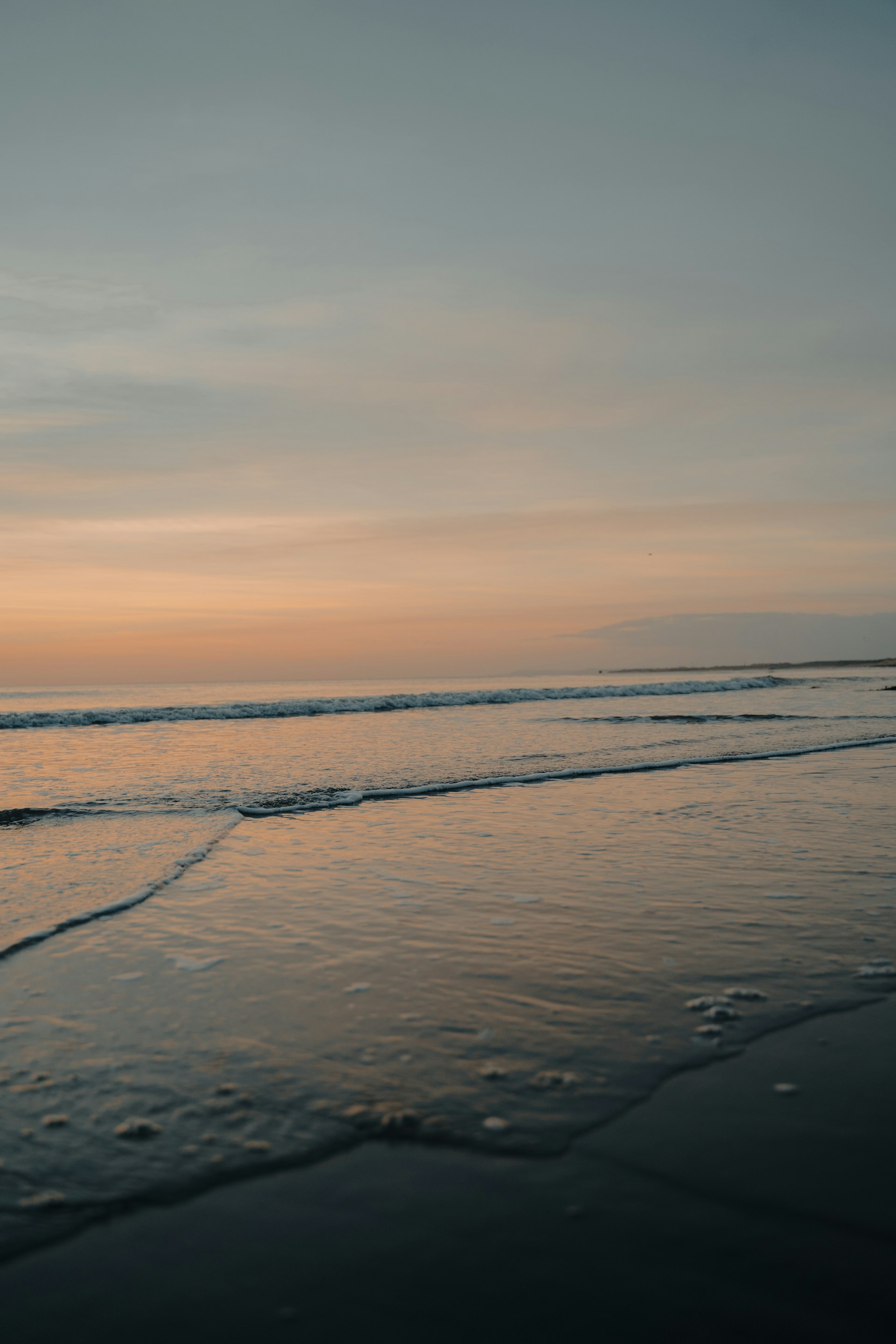 ocean waves crashing on shore during sunset