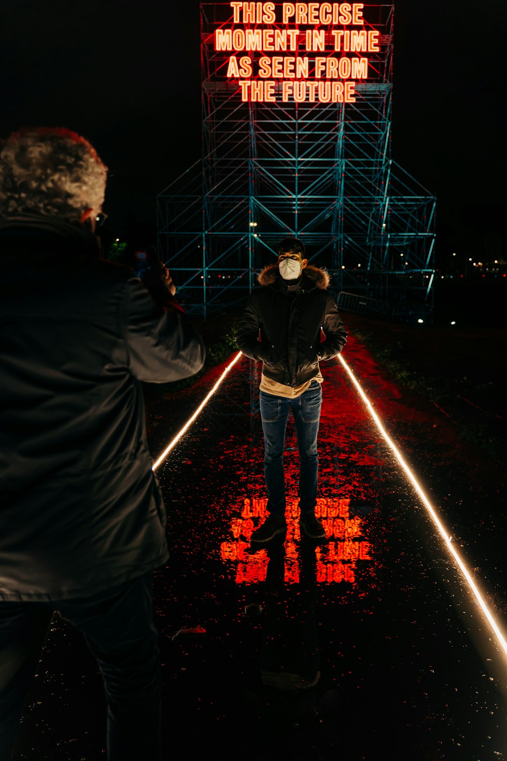 man in black jacket standing on the street during night time