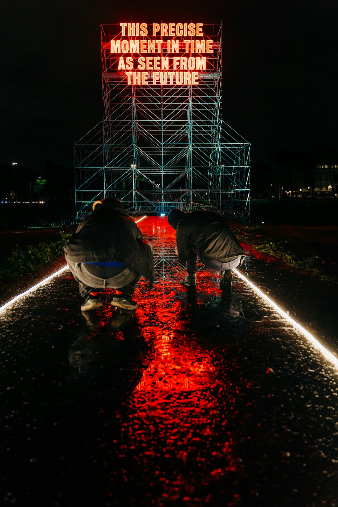 man in black jacket and blue denim jeans standing on road during nighttime