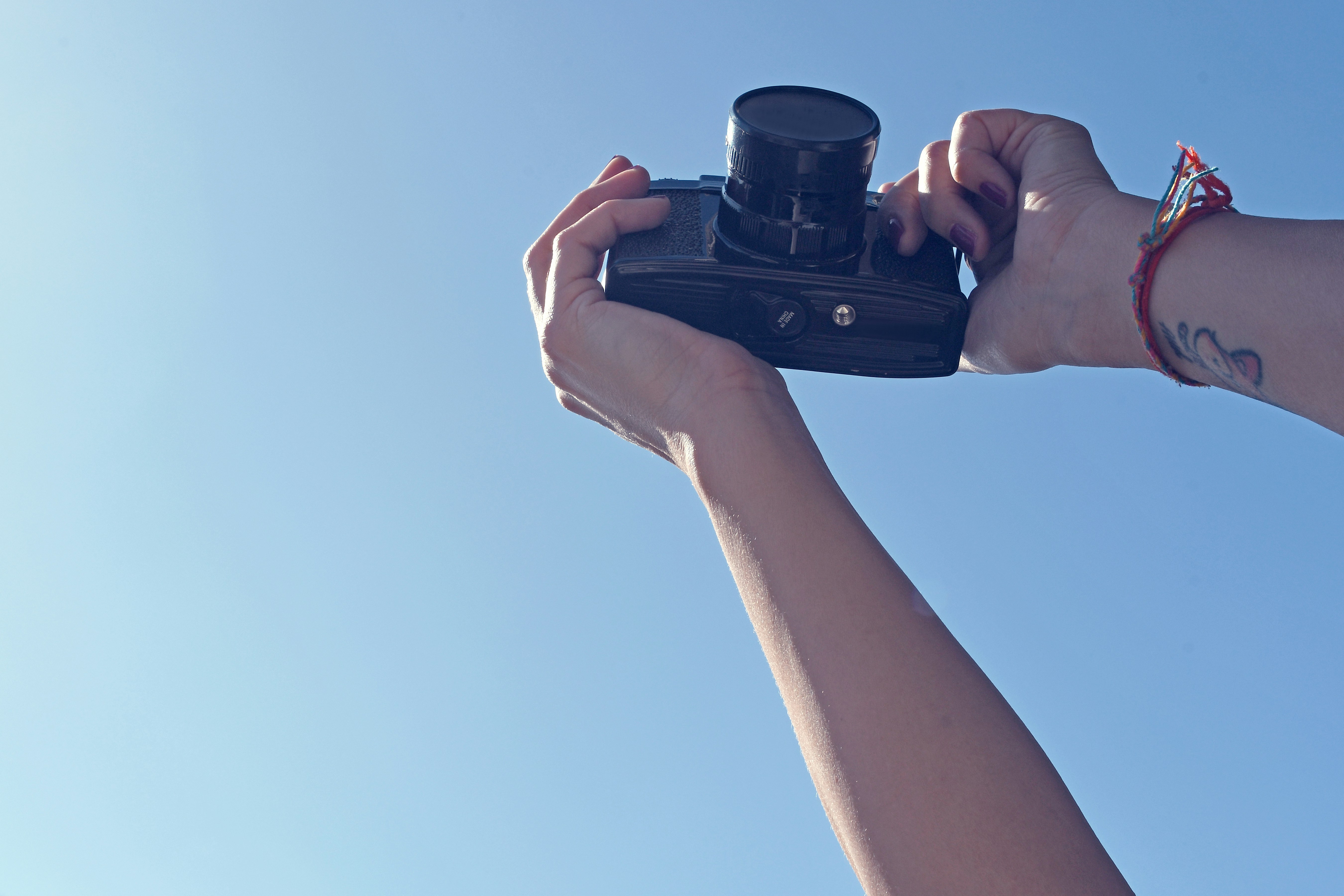 黒いデジタル一眼レフカメラを持っている人