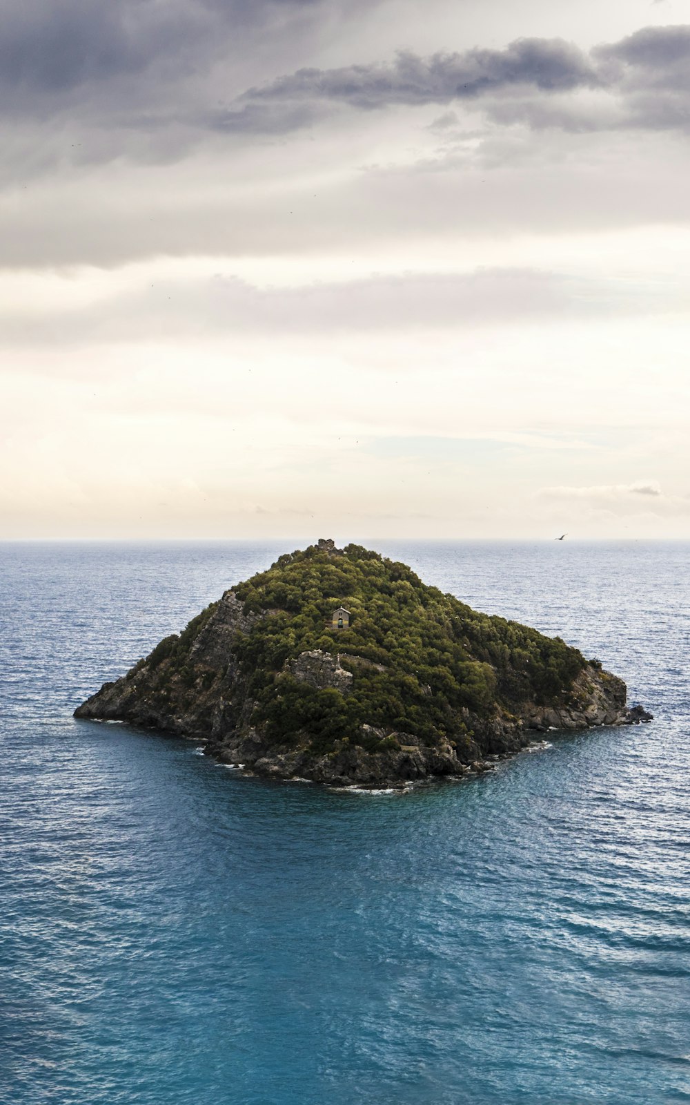 green and black rock formation on blue sea under white clouds during daytime