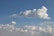A close-up of fluffy white clouds drifting over a calm blue horizon.