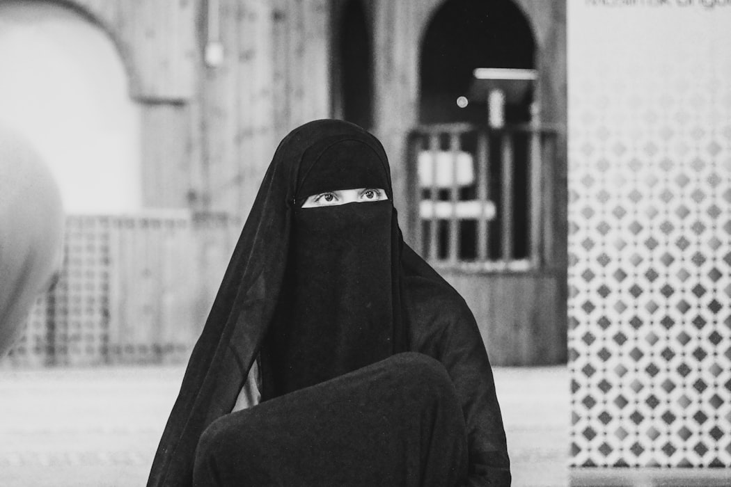 A black and white photo of a woman wearing a niqab.