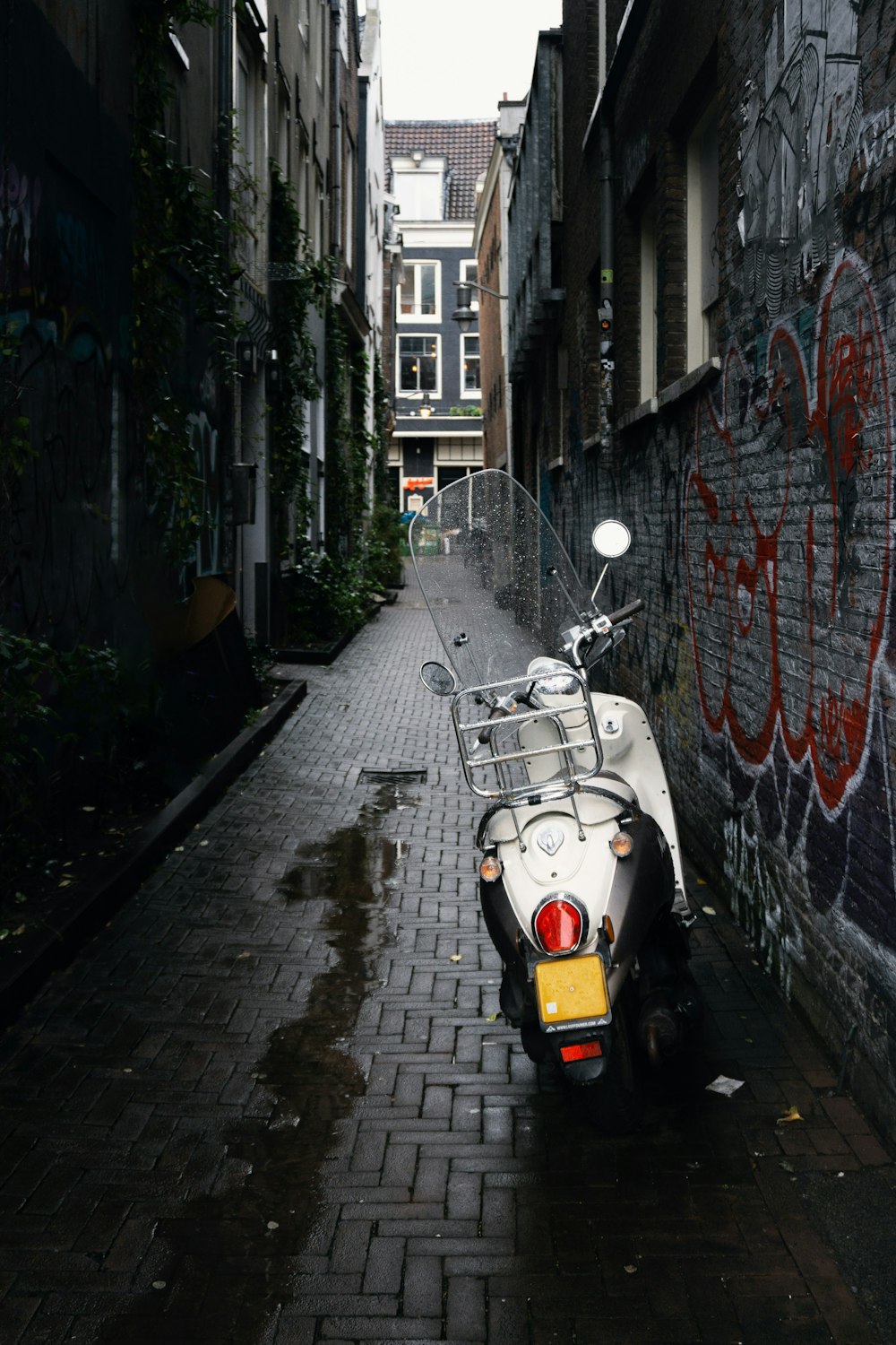 white motor scooter parked beside concrete building during daytime