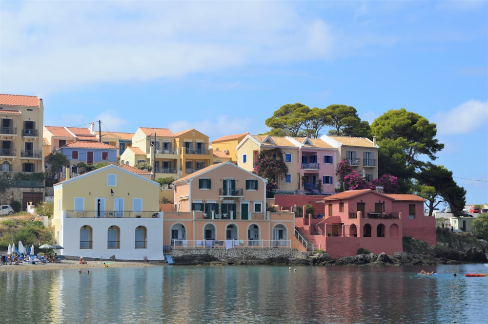 white and red concrete houses beside body of water during daytime