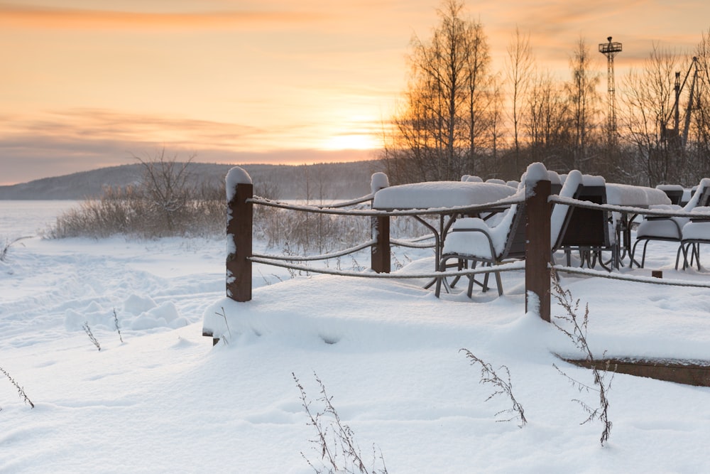 black wooden bench on snow covered ground during sunset