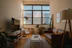 Cozy living room with sunlight streaming in, showing a spotless floor and tidy furniture.