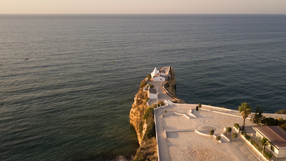 white concrete building on cliff near body of water during daytime