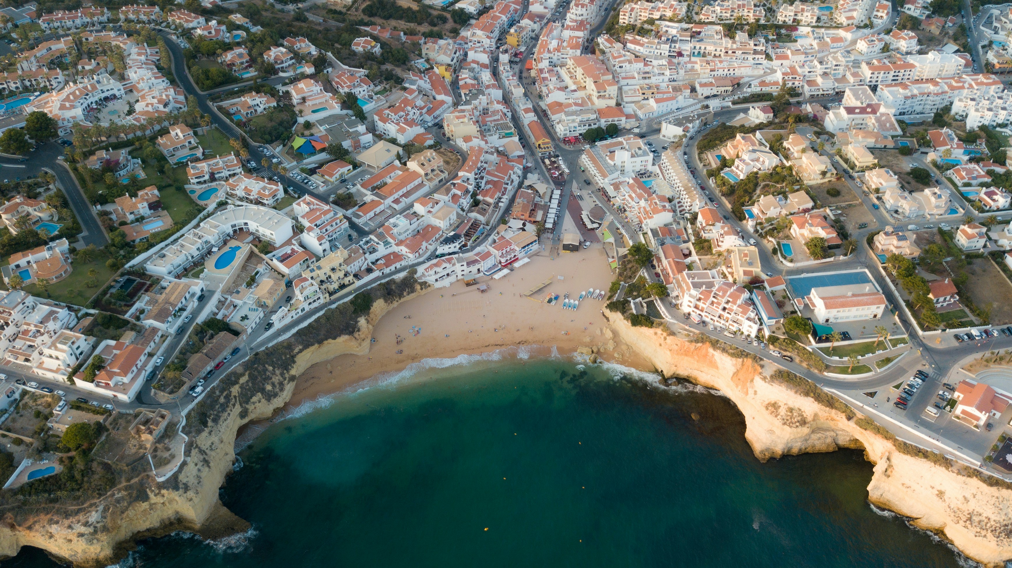 aerial view of city buildings near body of water during daytime, Little beach town in the south of Portugal seen from a drone.