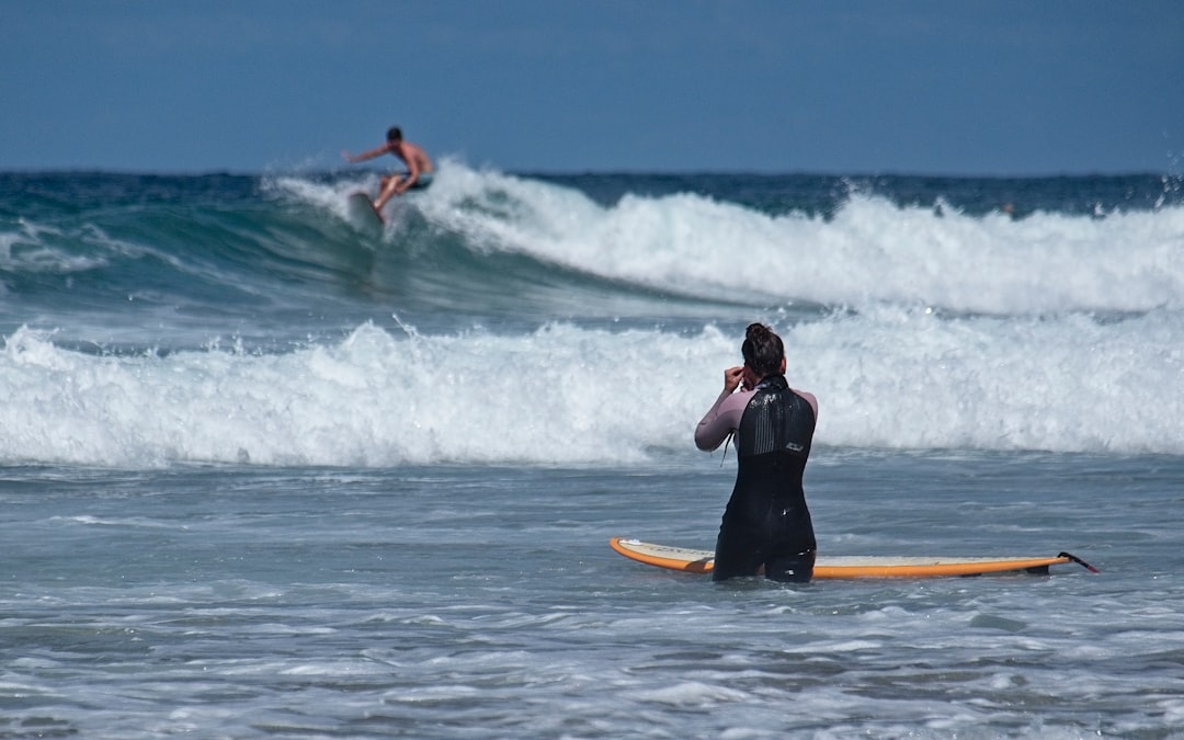 woman in black wetsuit surfing on sea waves during daytime