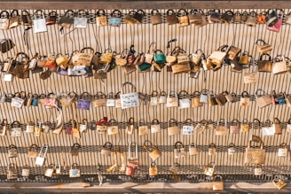 Numerous padlocks attached to a metal fence, each inscribed with different names, dates, or messages, symbolizing love or commitment.