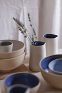 A collection of turned wooden bowls and small furniture pieces painted in soothing lavender and mint hues.