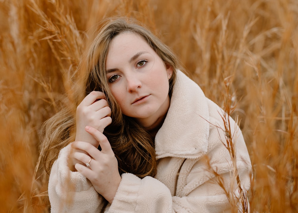 woman in white coat on brown grass field