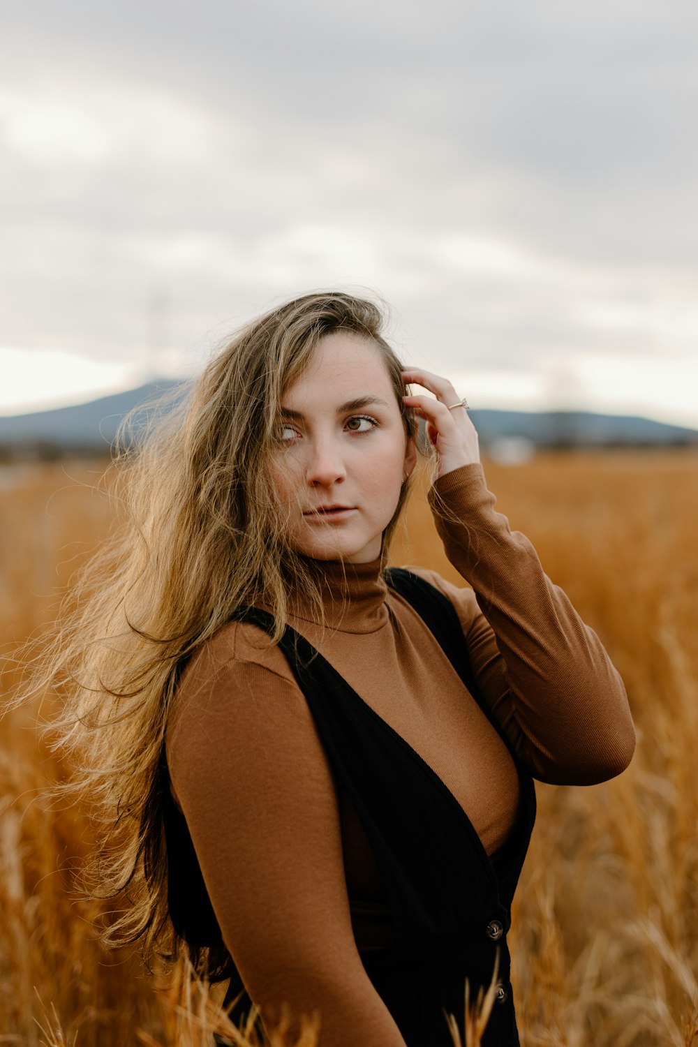 woman in black tank top standing on brown grass field during daytime