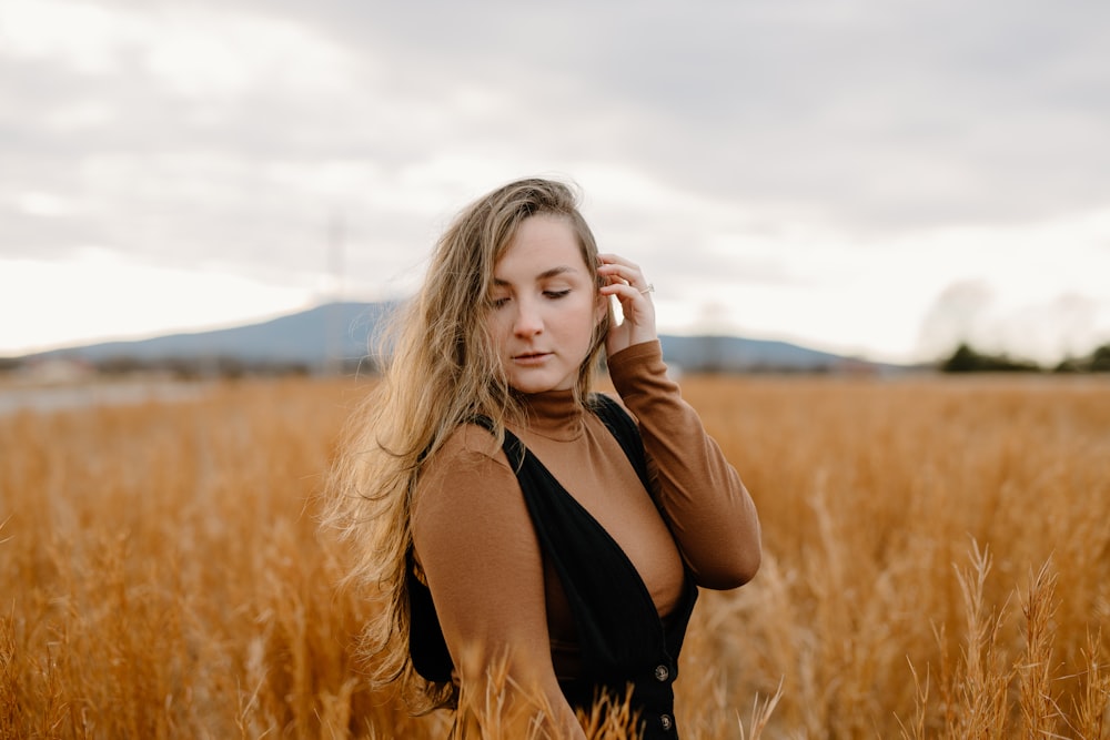 woman in black tank top standing on brown grass field during daytime