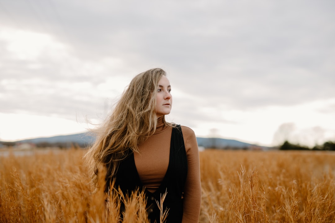 woman in black tank top standing on brown grass field during daytime