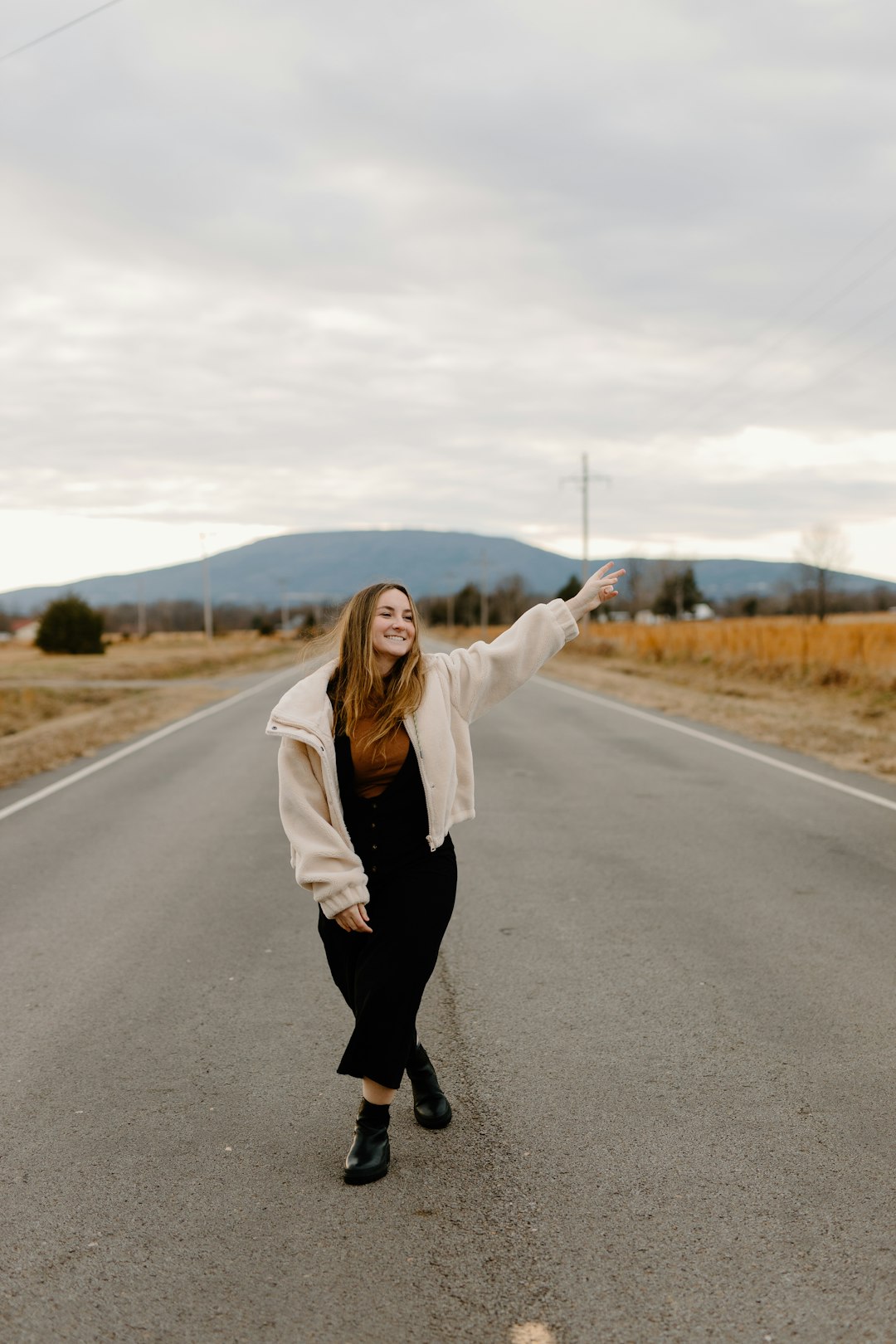 woman in white coat and black pants standing on road during daytime