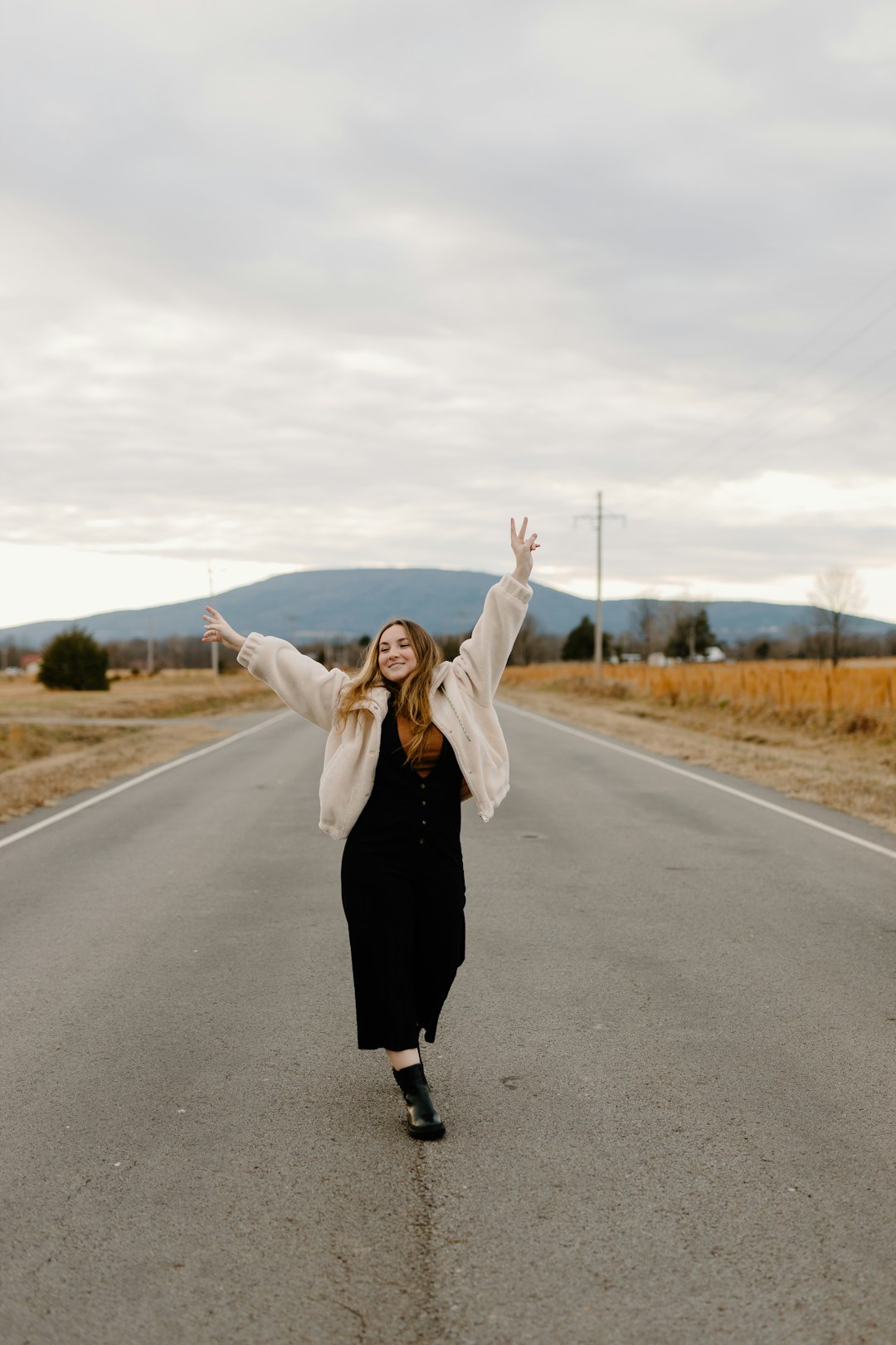 woman in black dress standing on road during daytime