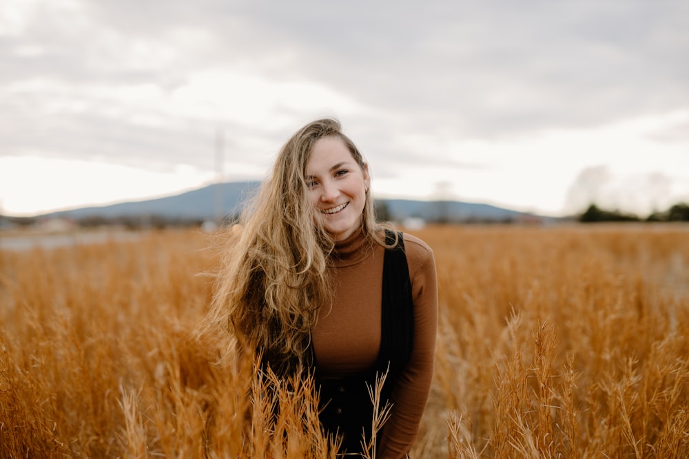 woman in black tank top standing on brown grass field during daytime