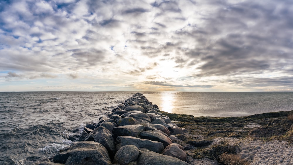 gray and black rocks near body of water under gray clouds