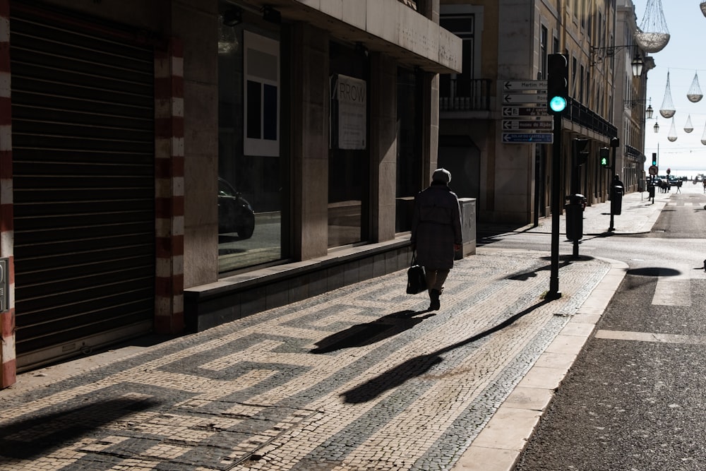 person in black coat walking on sidewalk during daytime