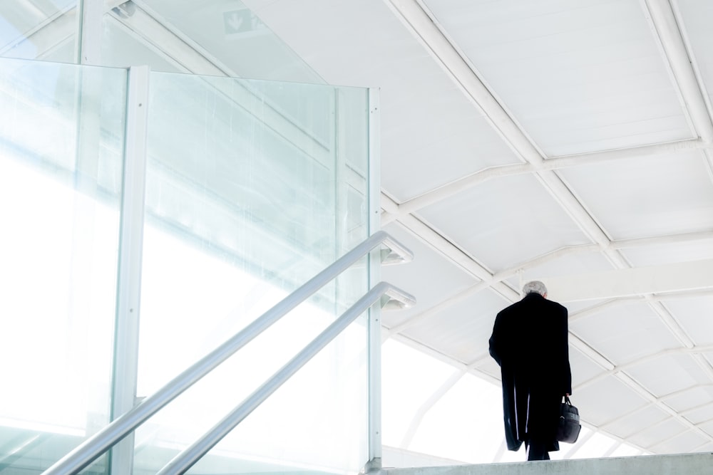 man in black suit standing on white staircase