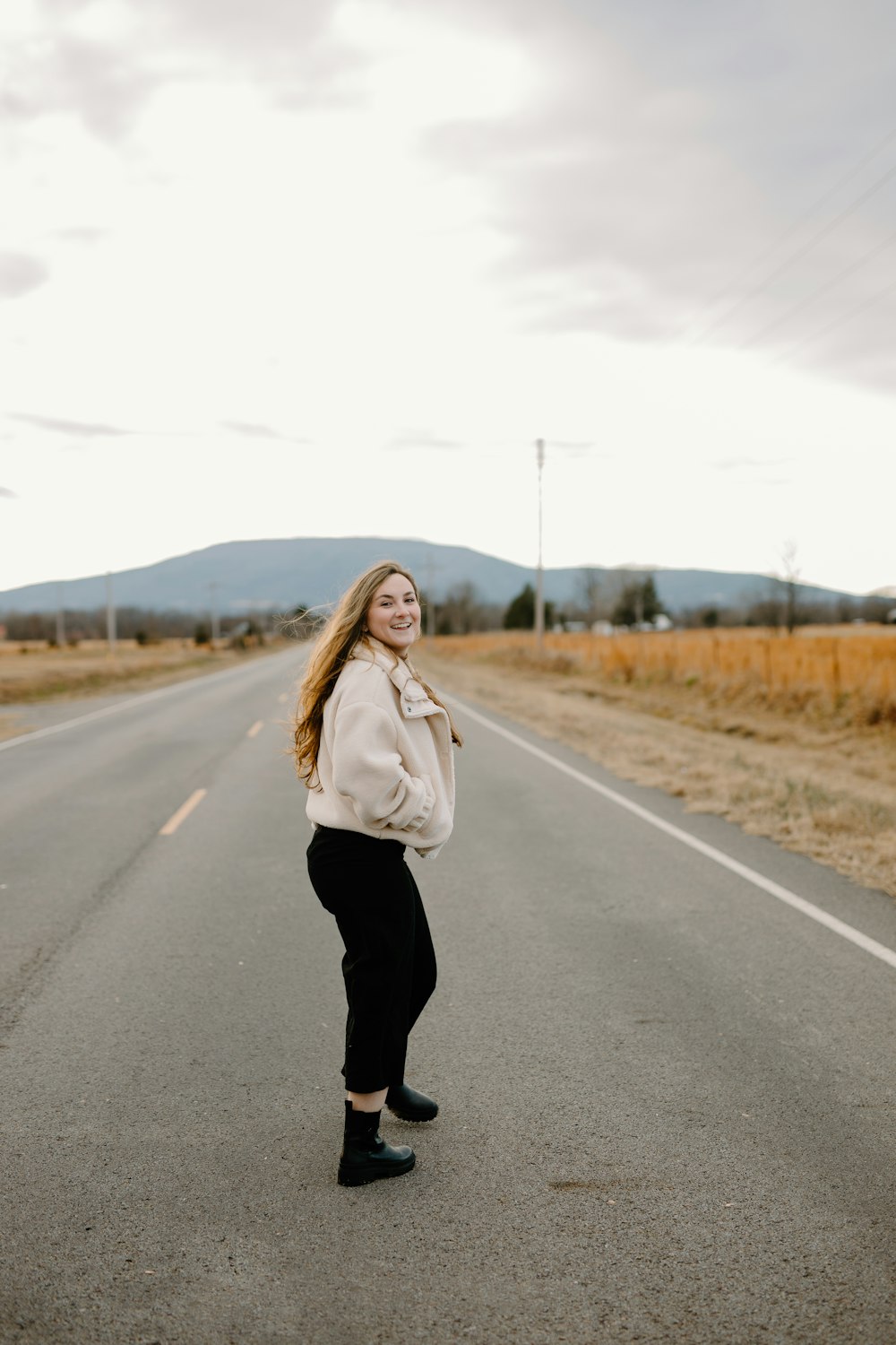 woman in white coat standing on road during daytime