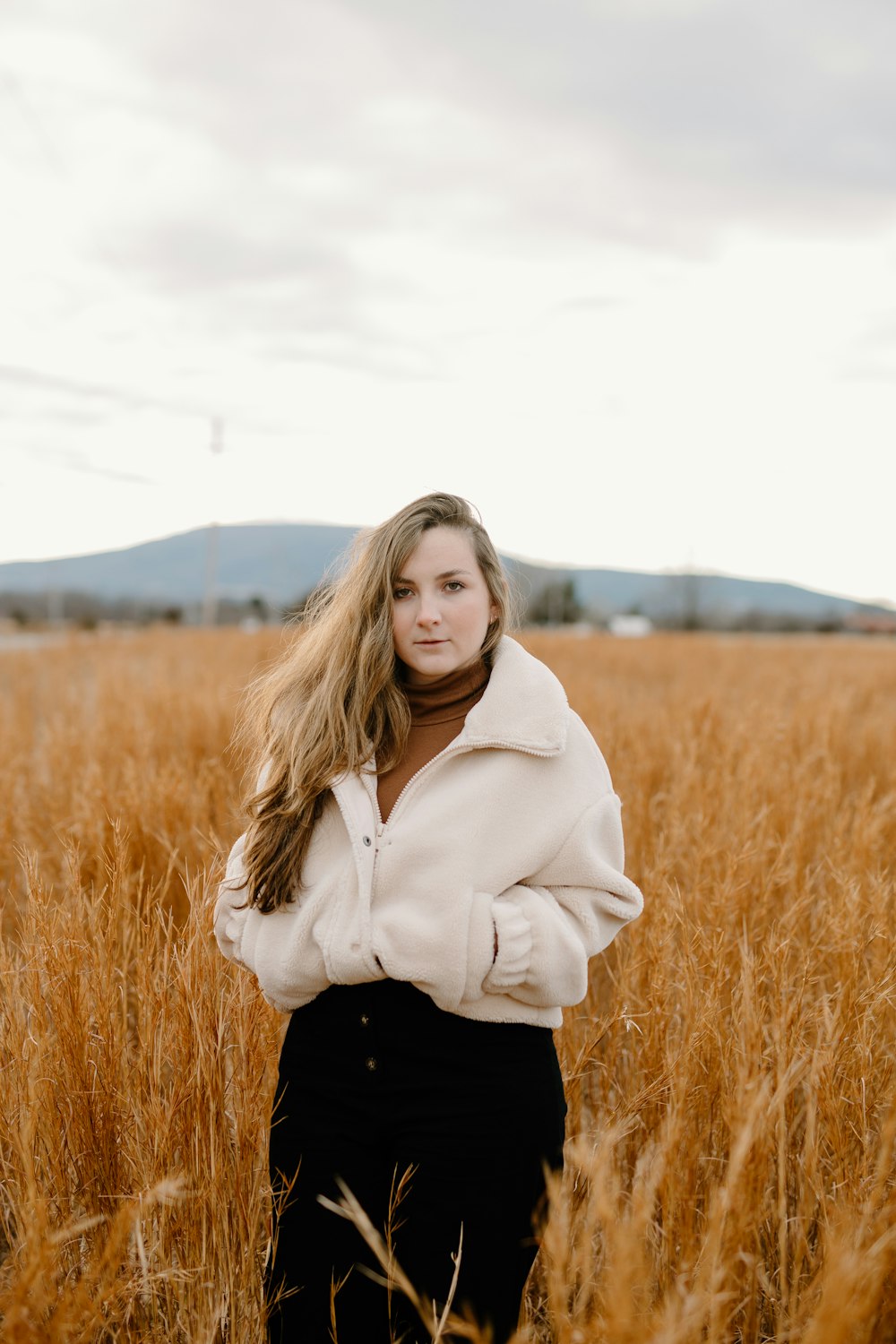 woman in white jacket standing on brown grass field during daytime