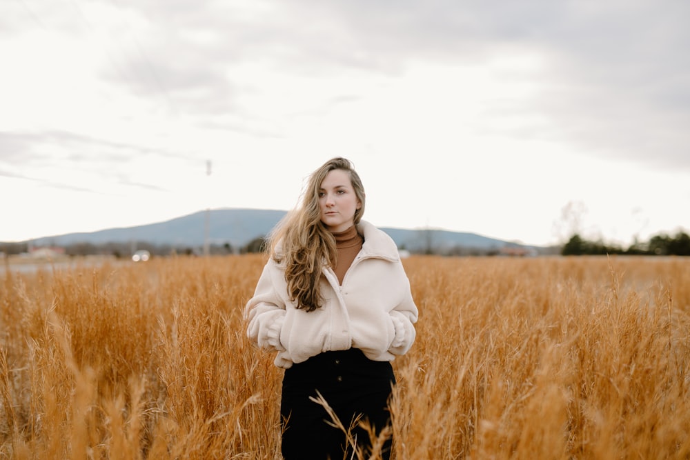 woman in white jacket standing on brown grass field during daytime