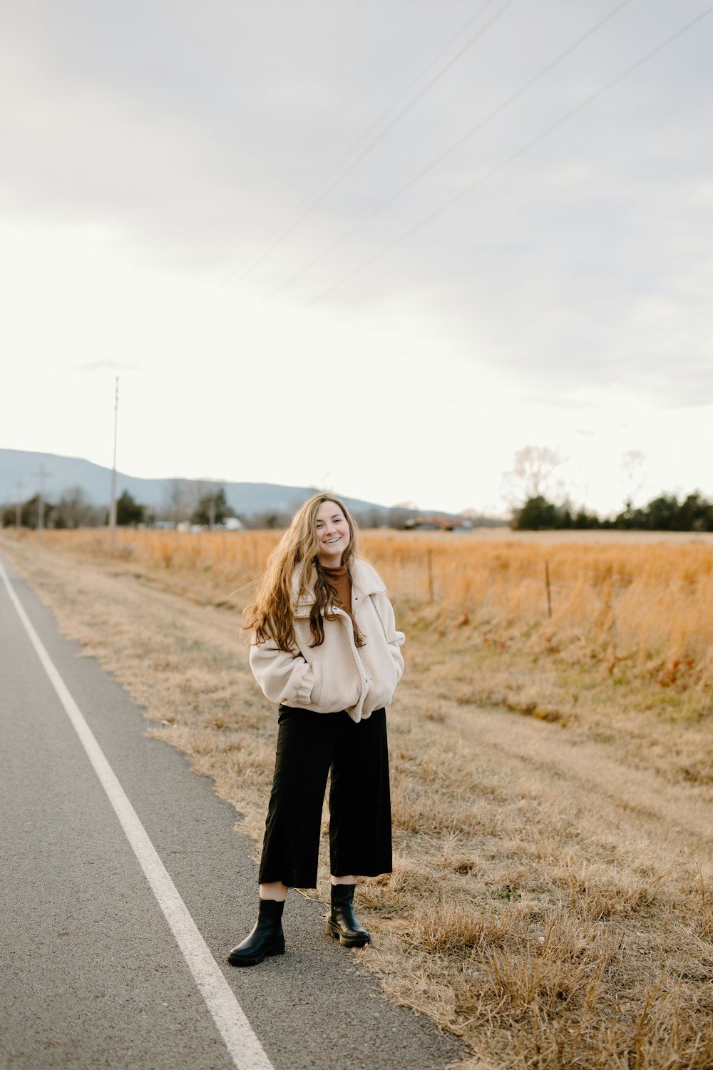 woman in white jacket standing on road during daytime